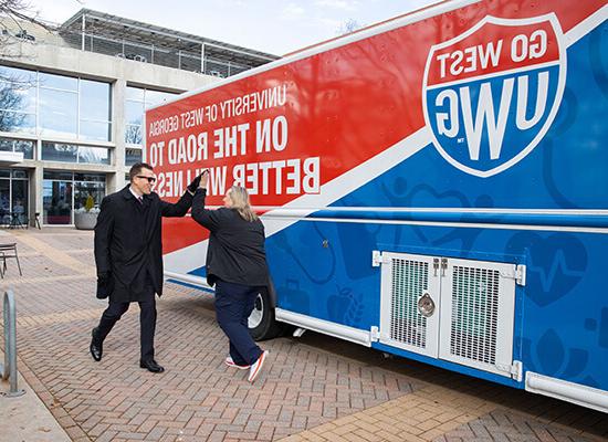 博彩平台推荐 President Brendan Kelly high fives Chief Wellness Officer Bridgette Stewart in front of 博彩平台推荐's mobile health unit.